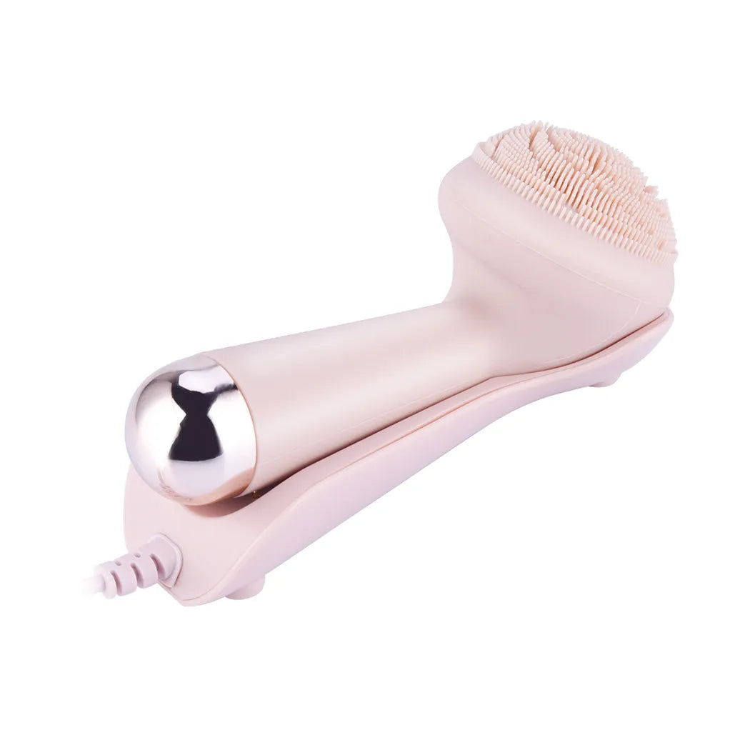 Side angle view of pink silicone facial cleansing brush showing soft bristle head and gold roller massage ball tip